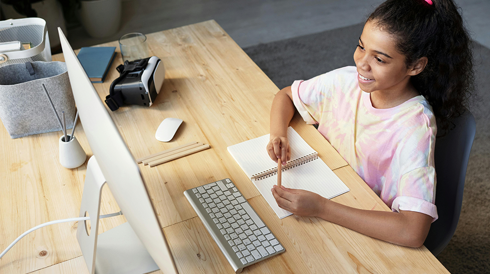 A young girl sat at a desk on an iMac